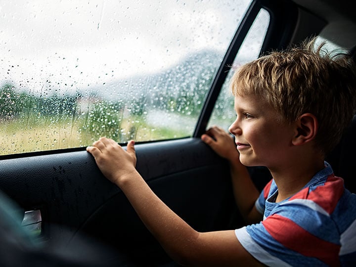 Automotive Environmental Testing with boy looking out a a car window during a rainy day