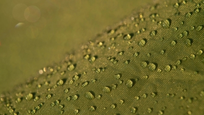 Water droplets on waterproof fabric.Water drops on a green waterproof fabric close-up macro photography.Water drops on a waterproof fabric. ( Water droplets on the tent fabric.)	
