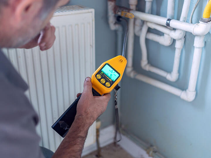 Adult male checking gas leak on boiler with digital gas detector